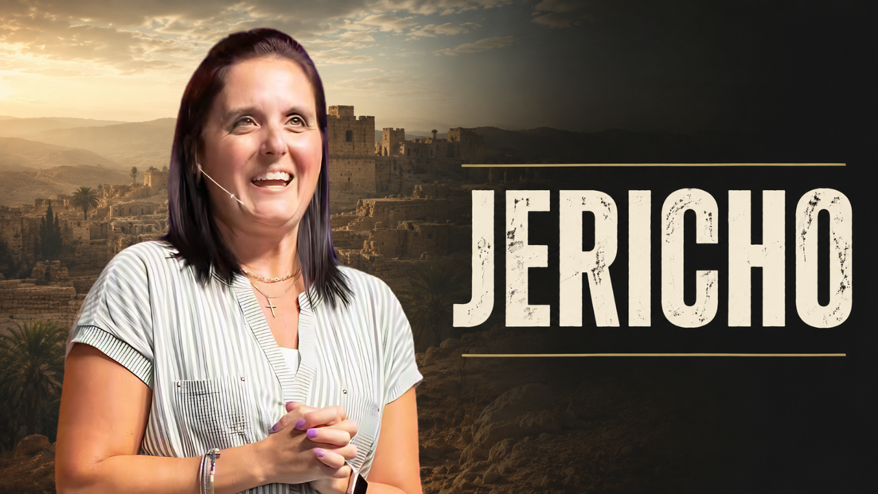 Smiling woman speaking on a stage with a large ‘JERICHO’ sign and desert backdrop behind her.